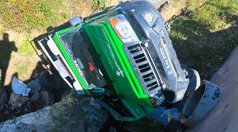 Nepal Police and local rescuers inspecting the wrecked jeep down a steep embankment in Ilam