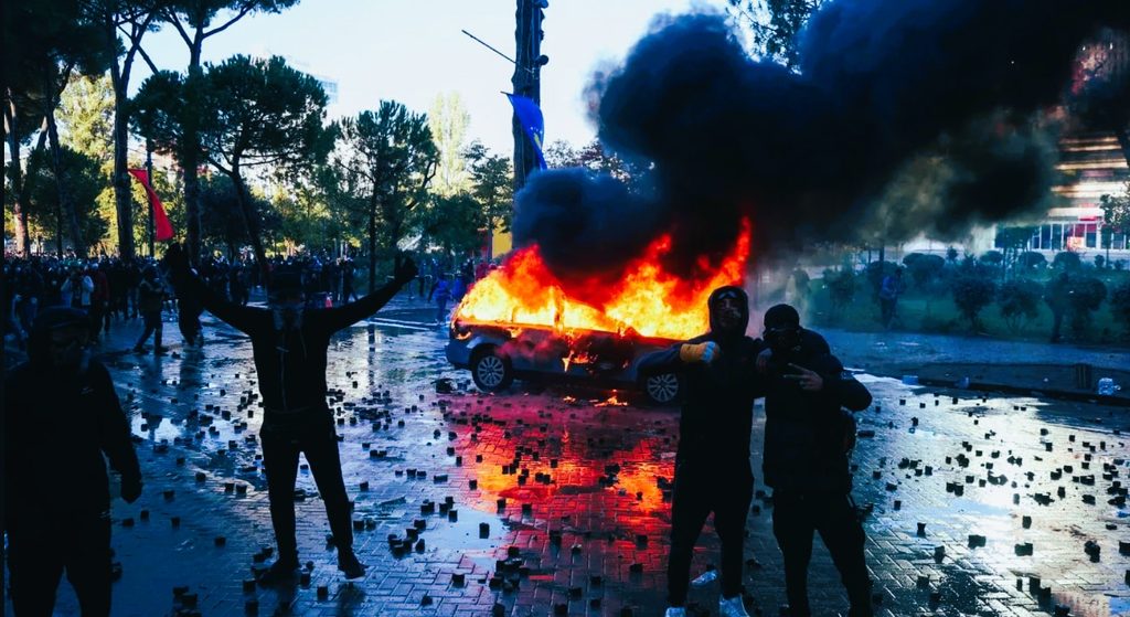 Albanian riot police deploying water cannons and tear gas against masked protesters along Dëshmorët e Kombit Boulevard in Tirana