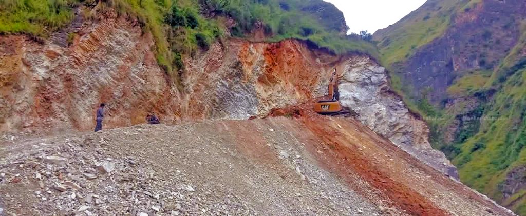 Police rescue personnel clearing dry landslide debris around the buried excavator at Bira Khola in Mugu district
