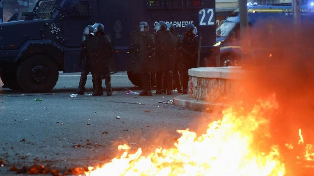 French riot police clashing with protesters in Paris amid tear gas and smoke