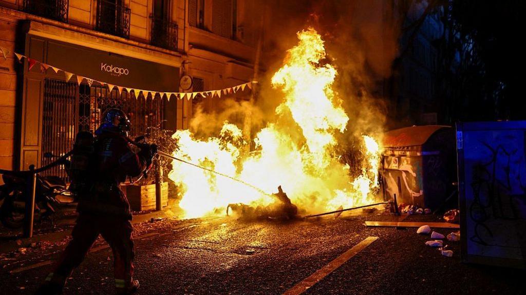 French riot police marching through tear gas smoke during protests in Paris