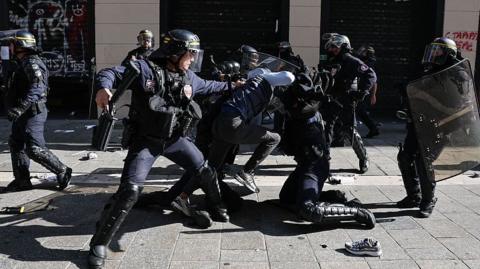 French riot police personnel standing near tear gas canisters and barricades during student protests in Paris