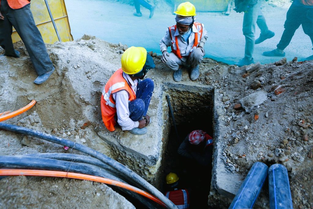 Nepal Electricity Authority technicians installing underground power cables along a street in Kathmandu